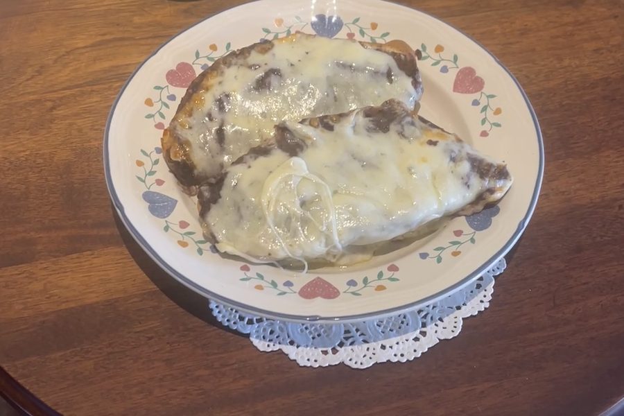 Sandpino's molletes with melted cheese on a floral plate at a wooden café table.